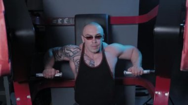 Profesyonel vücut geliştirici bir spor kulübünde simülatörde göğüs kaslarını çalıştırır..