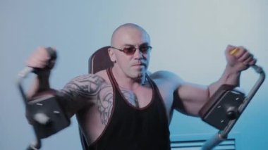 Profesyonel vücut geliştirici bir spor kulübünde simülatörde göğüs kaslarını çalıştırır..