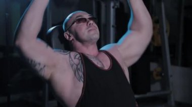 Profesyonel vücut geliştirici bir spor kulübünde kafasının üstüne dambıl kaldırır..