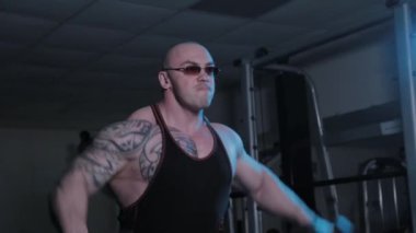 Profesyonel vücut geliştirici bir spor kulübünde dambıl kaldırıyor..