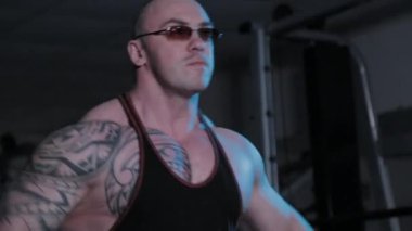 Profesyonel vücut geliştirici bir spor kulübünde dambıl kaldırıyor..