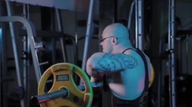 Profesyonel vücut geliştirici spor kulübünde halteri çenesine kaldırma egzersizi yapar..