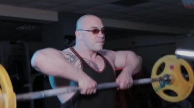 Profesyonel vücut geliştirici spor kulübünde halteri çenesine kaldırma egzersizi yapar..