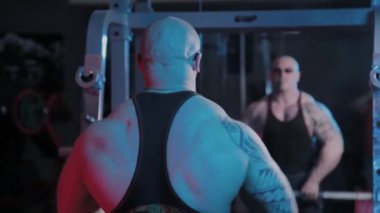 Profesyonel vücut geliştirici spor kulübünde halteri çenesine kaldırma egzersizi yapar..