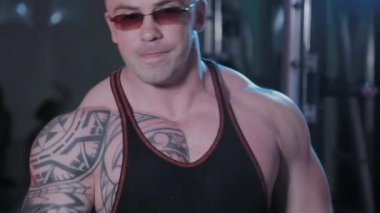 Profesyonel vücut geliştirici, bir spor kulübünde dambıllı bisepsler eğitir..