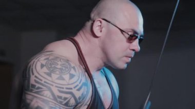 Profesyonel vücut geliştirici bir spor kulübünde trisepsleri blok simülatöründe eğitir..