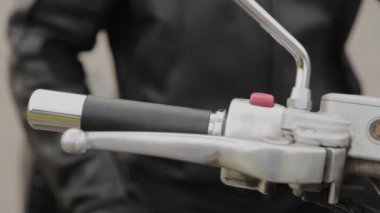 Motosikletli bir adam direksiyonu tutuyor..