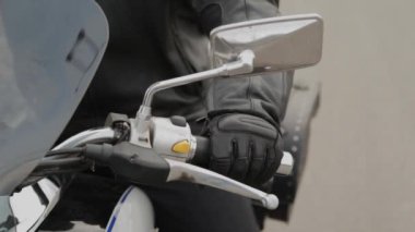 Motosikletli bir adam direksiyonu tutuyor..