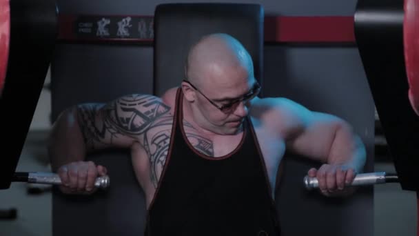 Professionell kroppsbyggare tränar bröstmusklerna på simulatorn i en sportklubb. — Stockvideo