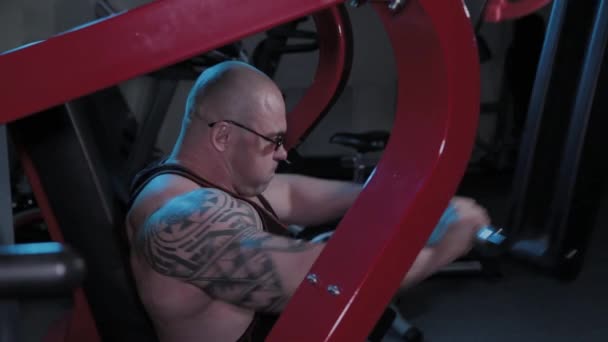 프로 보디빌더가 스포츠 클럽에서 시뮬레이터로 가슴 근육을 훈련 시킨다. — 비디오