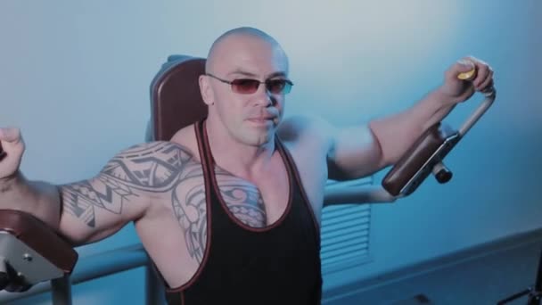 Professionell kroppsbyggare tränar bröstmusklerna på simulatorn i en sportklubb. — Stockvideo