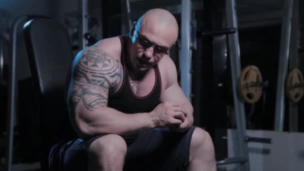 Professionele bodybuilder zittend op een bank in een sportclub. — Stockvideo