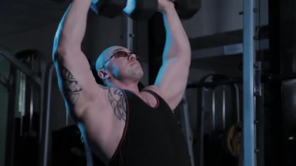 Professionele bodybuilder tilt halters over zijn hoofd in een sportclub. — Stockvideo