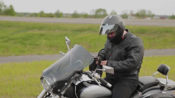 Man motorrijder op een motorfiets zet op apparatuur. — Stockvideo