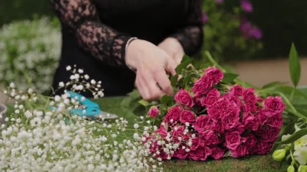 Fleuriste prend des fleurs dans ses mains pour un bouquet . — Video