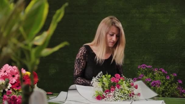Kwiaciarnia pakuje bukiet kwiatów w pięknym papierze. — Wideo stockowe
