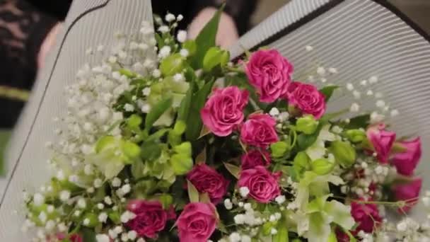 Bloemist verpakt een boeket bloemen in een mooi papier. — Stockvideo