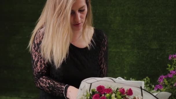 Bloemist verpakt een boeket bloemen in een mooi papier. — Stockvideo