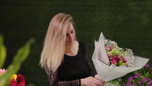 Florista embala um buquê de flores em um belo papel . — Vídeo de Stock