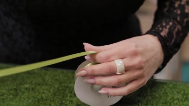 Fleuriste coupe des rubans pour décorer un bouquet . — Video