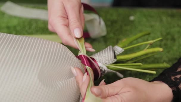 Florista amarra um buquê com belas fitas . — Vídeo de Stock