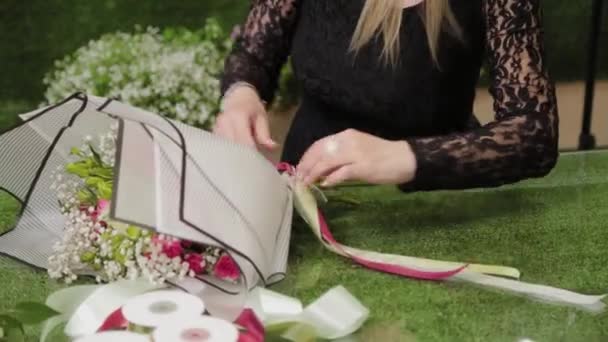 Bloemist bindt een boeket met mooie linten. — Stockvideo