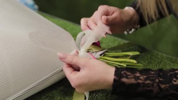 Florista amarra um buquê com belas fitas . — Vídeo de Stock