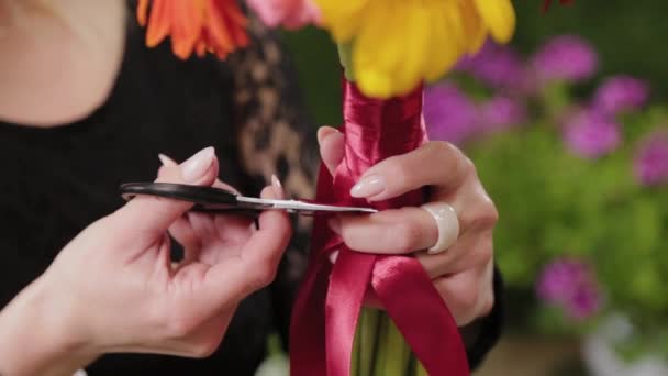 Флорист связывает красивый разноцветный букет с лентами . — стоковое видео