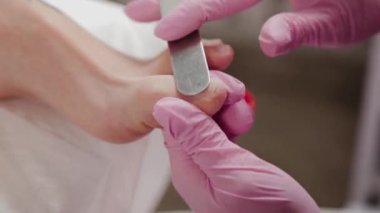 Pedikür ustası bir kadının ayak tırnaklarını keser..