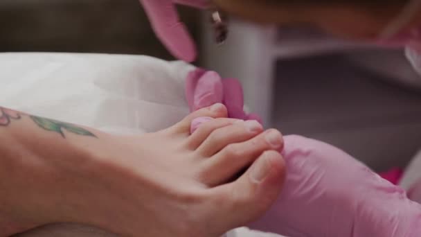 Pedicure master cuts cuticles on a womans leg. — 비디오