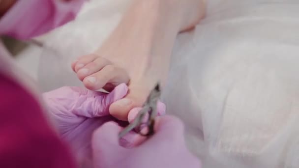 Pedicure master snijdt nagelriemen op een vrouwenbeen. — Stockvideo