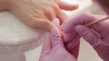 Manikürcü özel bir aletle tırnak etlerini kaldırıyor.