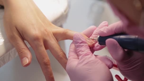 La manicura corta clavos con una máquina a un cliente en un salón de manicura . — Vídeos de Stock