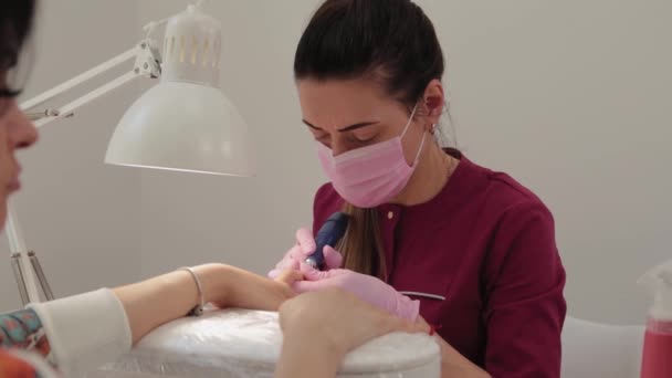 La manicura corta clavos con una máquina a un cliente en un salón de manicura . — Vídeo de stock