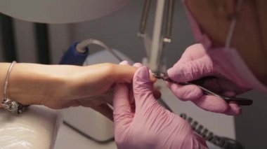 Manikürcü tırnak etlerini forseps ile söker..
