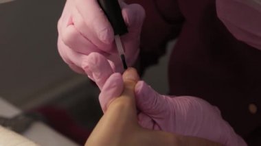 Manikürcü bir müşteriyle güzellik salonunda tırnaklarını cilalıyor..