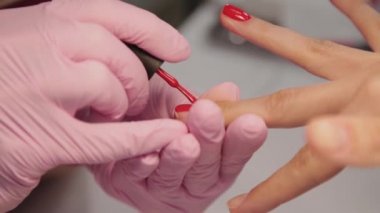 Manikürcü bir müşteriyle güzellik salonunda tırnaklarını cilalıyor..