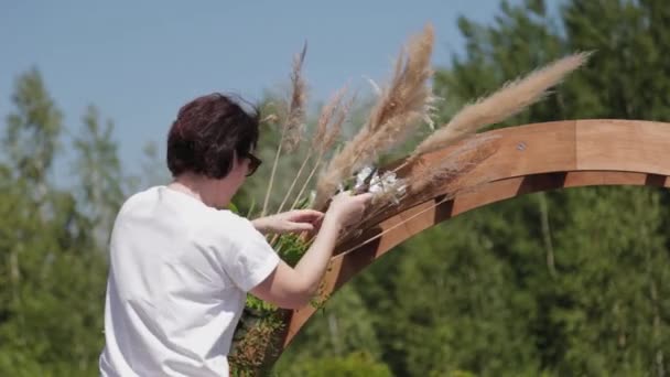 Hochzeitsdekorateur schmückt den Ort der Trauung mit frischen Blumen. — Stockvideo