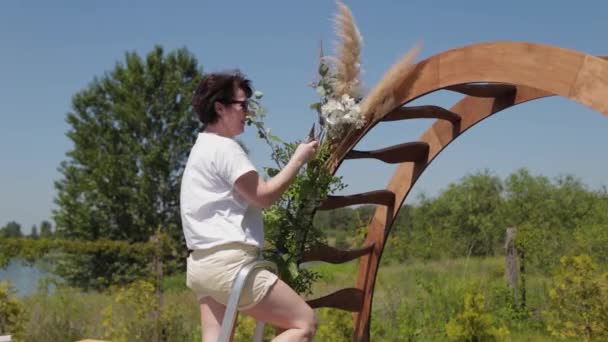 Bröllopsdekoratör dekorerar platsen för registrering av äktenskap med färska blommor. — Stockvideo