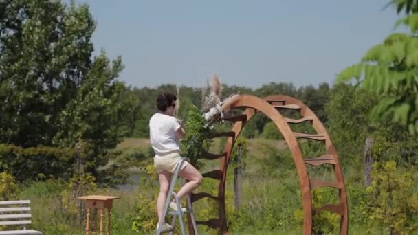 Bruiloft decorateur versiert de plaats van registratie van het huwelijk met verse bloemen. — Stockvideo