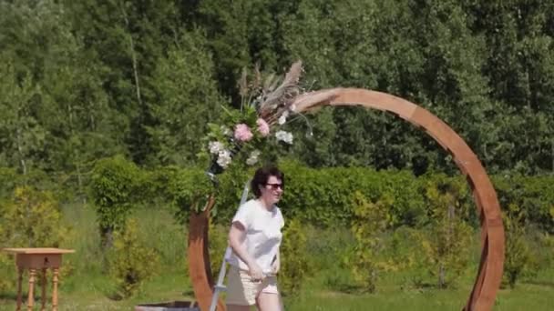 Bröllopsdekoratör dekorerar platsen för registrering av äktenskap med färska blommor. — Stockvideo