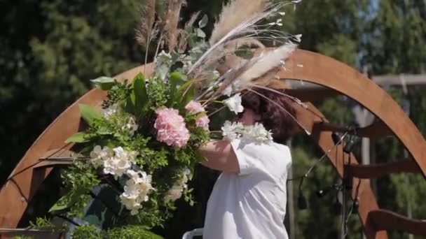 Decorador de bodas decora el lugar de registro del matrimonio con flores frescas . — Vídeo de stock