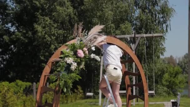 Bröllopsdekoratör dekorerar platsen för registrering av äktenskap med färska blommor. — Stockvideo