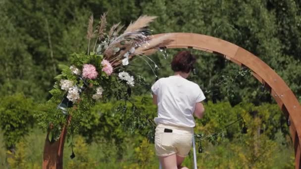 Décorateur de mariage décore le lieu d'enregistrement du mariage avec des fleurs fraîches. — Video