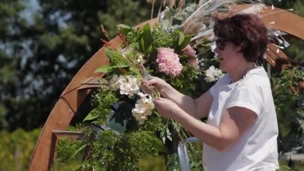 Decorador de bodas decora el lugar de registro del matrimonio con flores frescas . — Vídeos de Stock