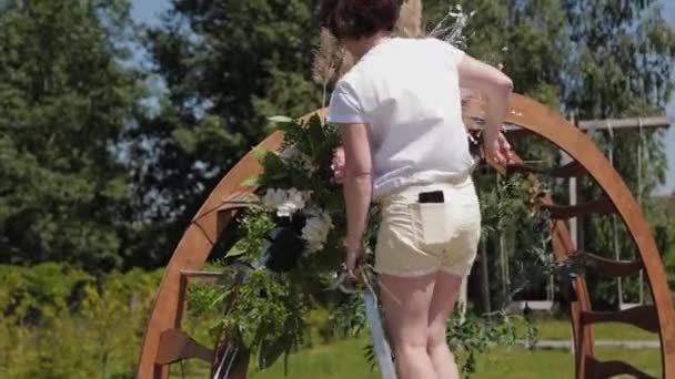 Decorador de bodas decora el lugar de registro del matrimonio con flores frescas . — Vídeo de stock