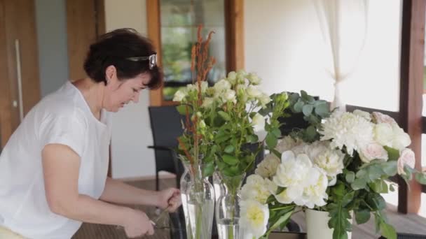 Hochzeitsdekorateur schmückt Blumen auf Tischen. — Stockvideo