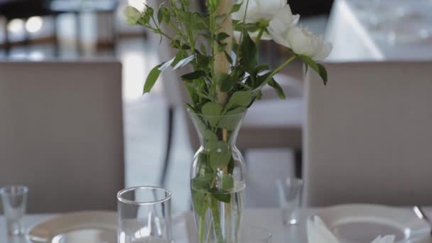 Hermosas flores en un jarrón de vidrio en la mesa festiva . — Vídeos de Stock