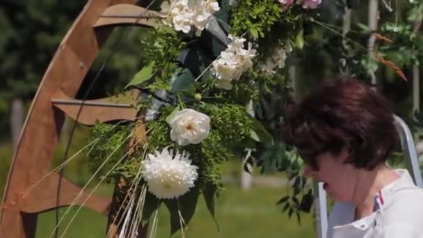 Decorador de bodas decora el lugar de registro del matrimonio con flores frescas . — Vídeos de Stock