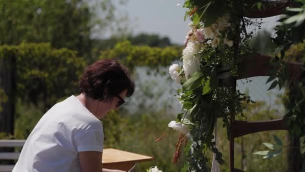 Bruiloft decorateur versiert de plaats van registratie van het huwelijk met verse bloemen. — Stockvideo